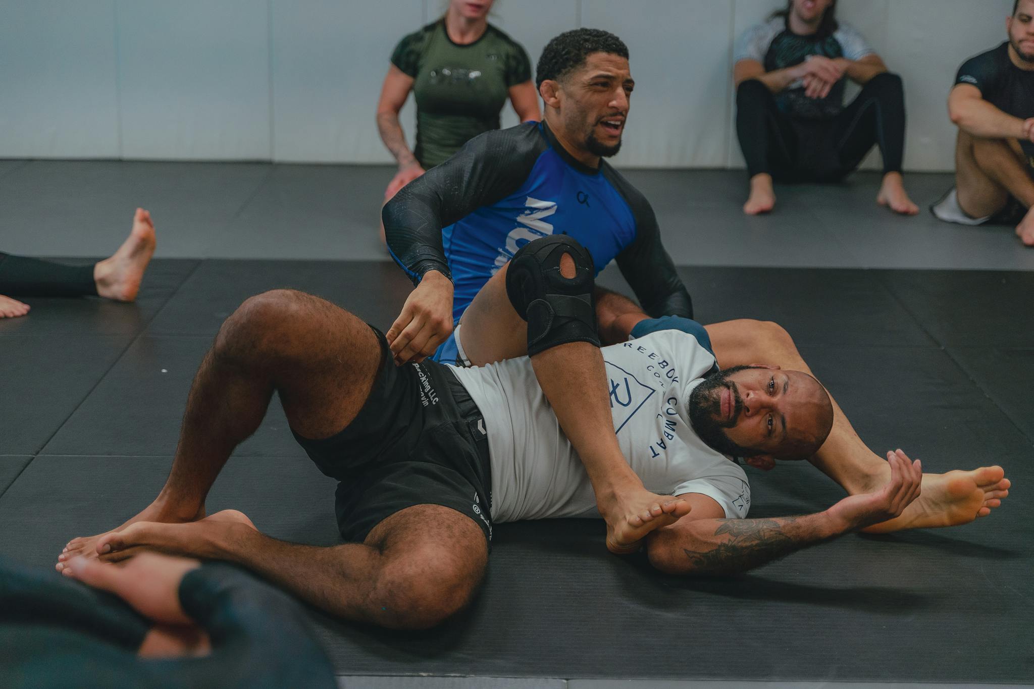 Two men engaged in a grappling training session at a martial arts gym, showcasing technique and focus.